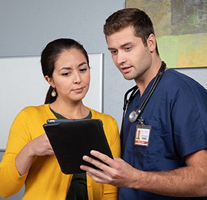 Healthcare provider with digital tablet talking to woman.