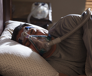 Man sleeping in bed wearing BiPAP mask.