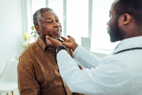 Doctor examining patient's neck and throat.