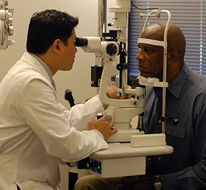 Health care provider examining man's eyes.